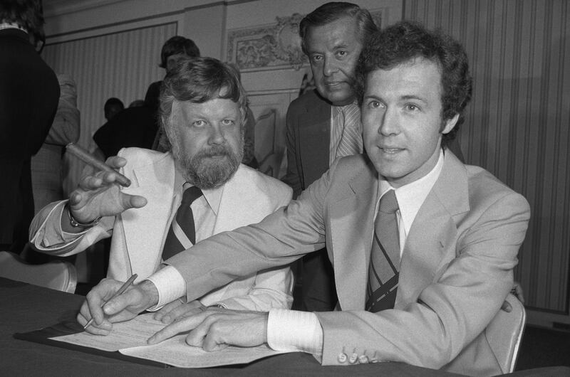 Franz Beckenbauer signing his contract with the New York Cosmos as club president Clive Toye (left) and chairman of the board Neguhii Ertegun (centre) look on. Photograph: Bettman archive