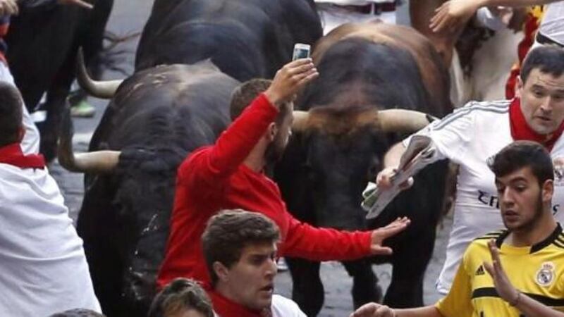 A Pamplona runner holds up his phone inches from the bulls. Photograph: Rafa Rivas/AFP/Getty Images