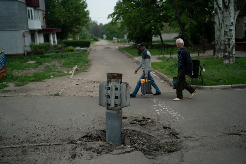 People walk past a rocket wedged in the ground in Lysychansk. Photograph: Leo Correa/AP