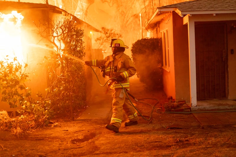 A firefighter works to suppress a burning home in Altadena, California. Photograph: Kyle Grillot/The New York Times
                      