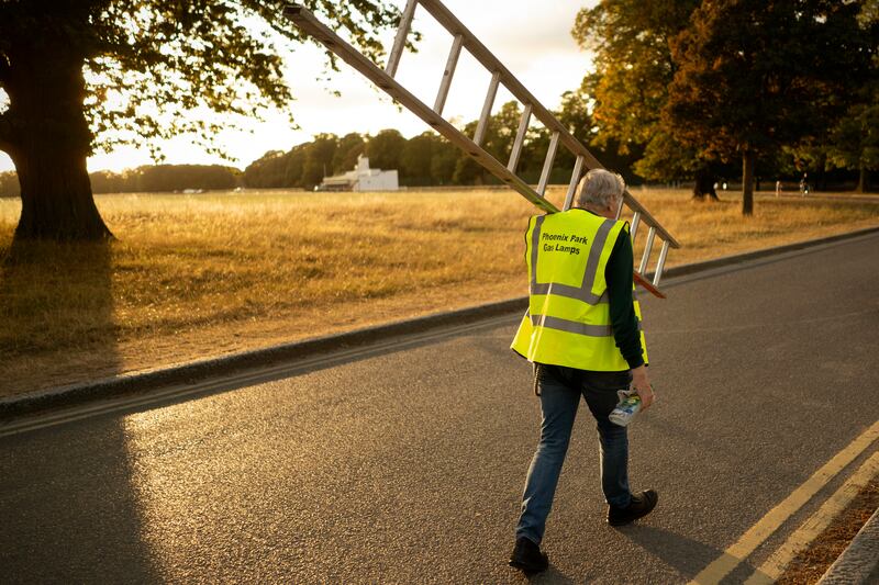 As the autumn days grow shorter, the lamplighters' role takes on added importance, lighting a way for evening walkers through the park. Photo: Chris Maddaloni/The Irish Times
