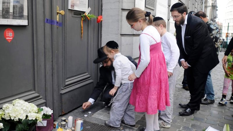 A family lights candles at the Jewish Museum, site of a shooting in central Brussels today. Belgian police are hunting today for an assailant who shot dead four people at the  museum yesterday. Photograph: Reuters