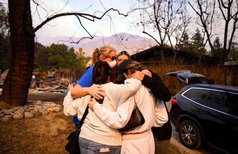 A family cries while embracing at their burned home during the Eaton fire in the Altadena area of Los Angeles county, California. Photograph: JOSH EDELSON/AFP via Getty Images