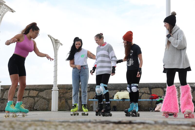 Journalist Niamh Donnelly (centre, striped grey jumper) being given a helping hand to get started in roller skates.  Photograph: Nick Bradshaw/ The Irish Times