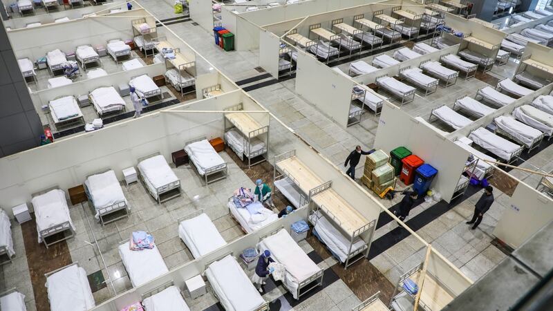 Medical staff members and workers setting up beds  at an exhibition centre converted into a hospital in Wuhan. Photograph: STR/AFP via Getty Images