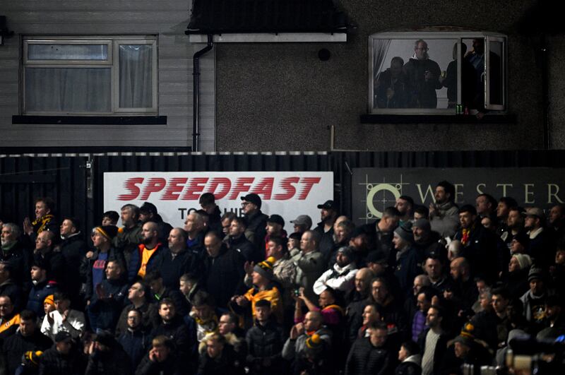 Newport fans stand in the window of a property overlooking the Rodney Parade stadium during the FA Cup clash with Manchester United. Photograph: Justin Tallis/AFP via Getty Images 