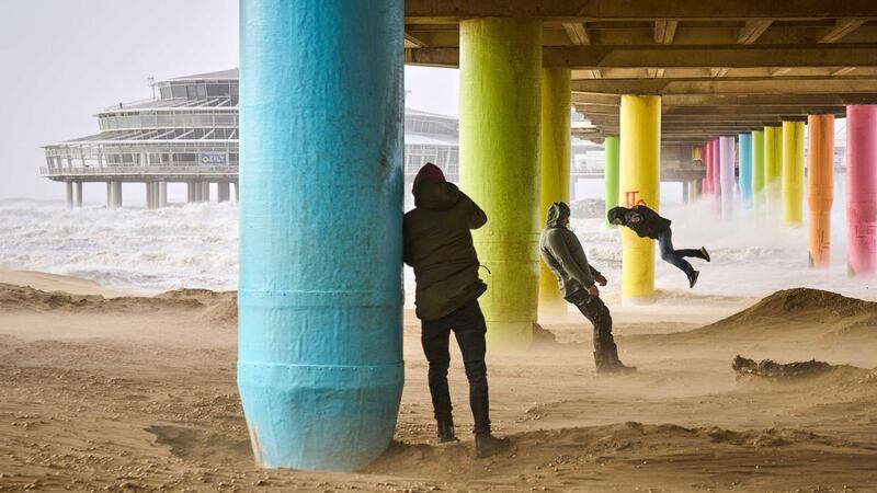 People play against the wind on the beach of Scheveningen in the Netherlands. There were very strong wind gusts of up to 120km/h. Photograph: Phil Nijhuis