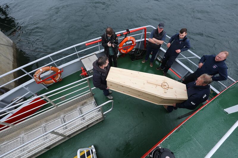 The coffin containing the 13 skulls is lifted off the ferry on its way to the burial site at the ruins of St Colman's Abbey. Photograph: Nick Bradshaw for The Irish Times