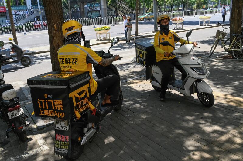 Delivery workers wait on their scooters: 'We have to ride fast but the road is very slippery and people can easily have accidents, like a car crash or falling off the bike.' Photograph: Pedro Pardo/AFP