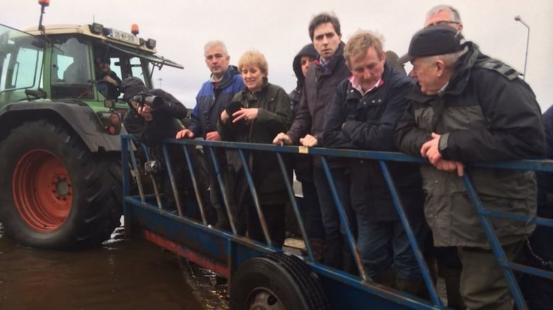 Taoiseach Enda Kenny visits flooded parts of Athlone, Co Westmeath, on Thursday afternoon on  a trailer drawn by a tractor. To his right are Minister of State Simon Harris and  Minister for Arts, Heritage and the Gaeltacht Heather Humphreys: Photograph: Fergal O’Brien/Twitter