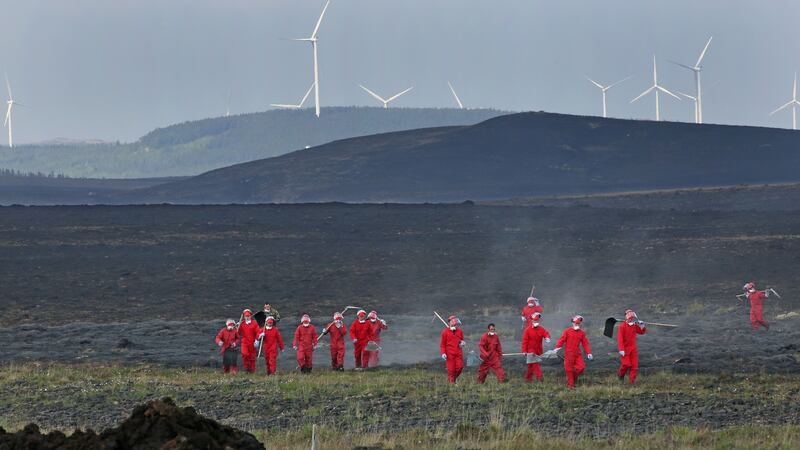 The scorched land with the wind turbines at Cloosh Valley behind as members of the Defence Forces make their way across bogland after extinguishing gorse fires near Inverin in Connemara on Wednesday. Photograph: Joe O’Shaughnessy