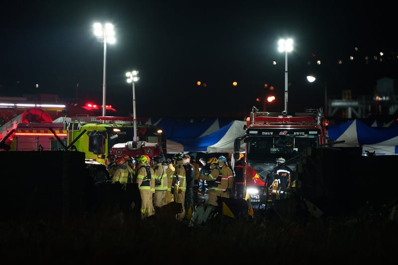 Firefighters and investigators at the scene of the Jeju Air passenger jet crash at  Muan International Airport, South Korea, on Sunday night. Photograph: Chang W Lee/New York Times
                      