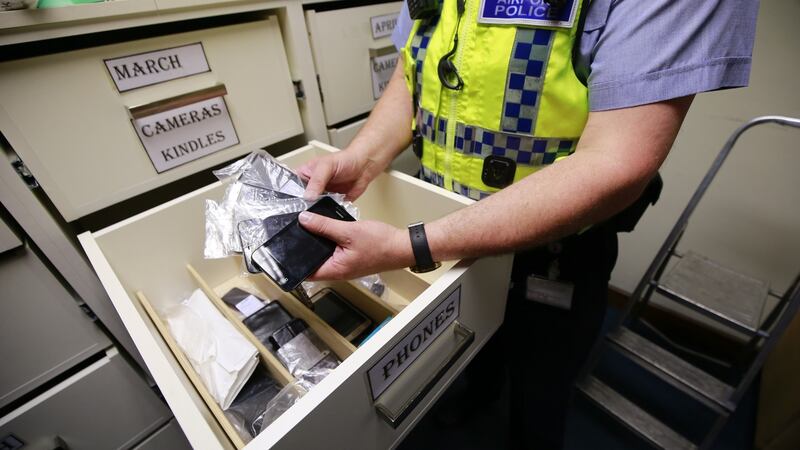 An officer display a small proportion of recovered mobile phones. Photograph: Nick Bradshaw