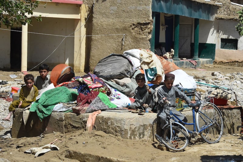 Children sit with their families belongings outside their houses damaged by flood waters after heavy monsoon rains in Quetta on August 27, 2022. - Thousands of people living near flood-swollen rivers in Pakistan's north were ordered to evacuate on August 27 as the death toll from devastating monsoon rains neared 1,000 with no end in sight. Photo by Banaras KHAN / AFP