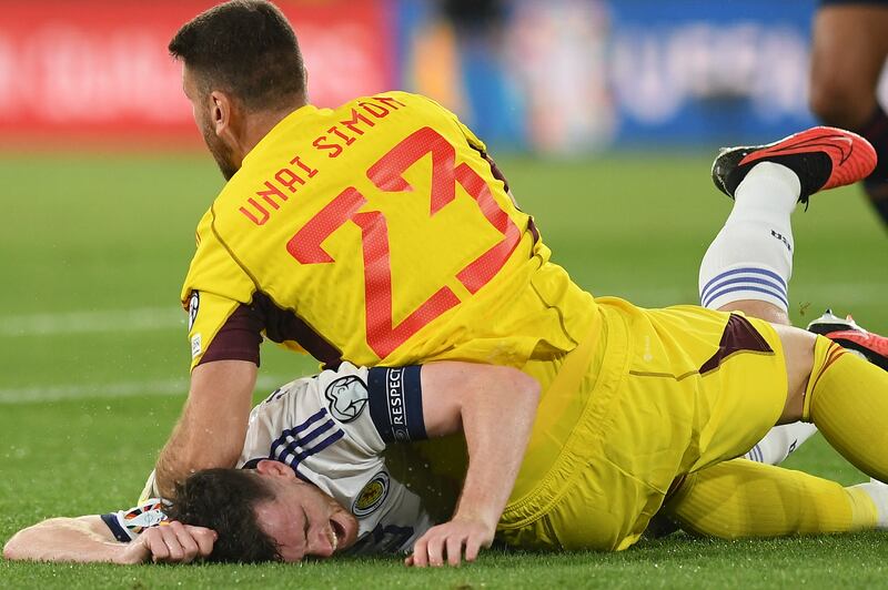 Spain's goalkeeper Unai Simon falls on Scotland's defender #03 Andrew Robertson. Photograph: Jorge Guerrero/AFP via Getty Images.  