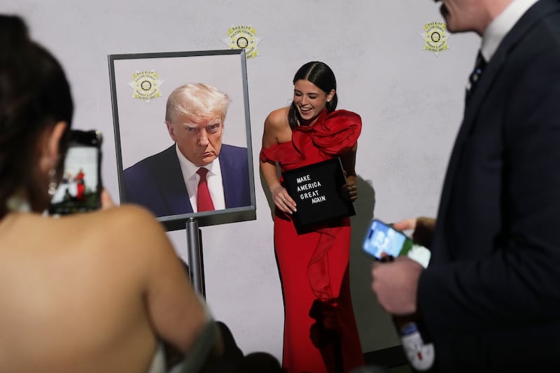 Attendees take photos with President Donald Trump’s mugshot during the Liberty Ball. Photograph: Kirsten Luce/The New York Times
                      