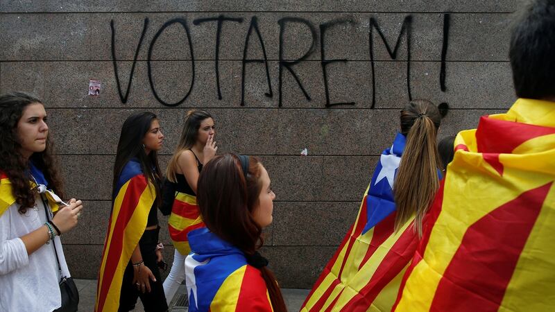 Students wear Catalan separatist flag during a demonstration in favour of the banned independence referendum, in Barcelona. The graffiti reads “We will vote!” Photograph: Jon Nazca/Reuters