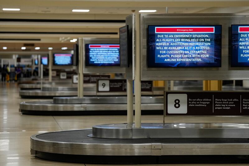 Screens at the baggage claim display an emergency alert message at Ronald Reagan Washington National Airport in Arlington, Virginia. Photograph: Kent Nishimura/The New York Times
                      