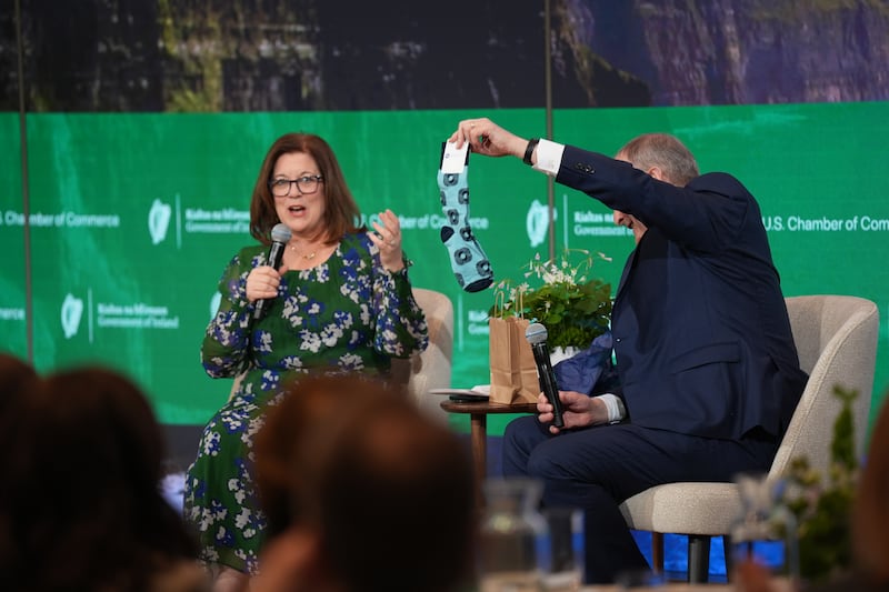 Taoiseach Micheál Martin holds up a pair of Chamber of Commerce socks as he talks to US Chamber of Commerce CEO Suzanne Clark in Washington DC. Photograph: Niall Carson/PA Wire

