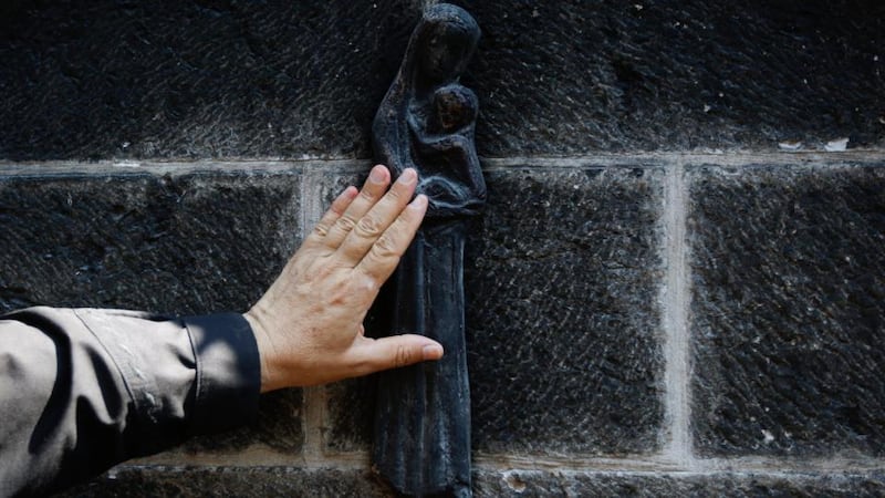 A cleric touches a charred statue of the Virgin Mary as he inspects the damage caused to the complex. Photograph: Atef Safadi/EPA