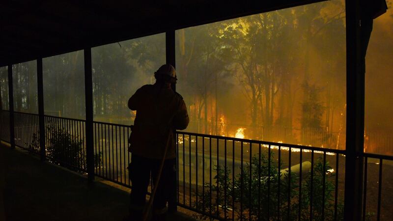 RFS volunteers and NSW Fire and Rescue officers protect a home on Wheelbarrow Ridge Road being impacted by the Gospers Mountain fire near Colo Heights south west of Sydney on Wednesday. Photograph: Dean Lesins/EPA