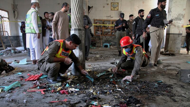 Rescue workers and police officers examine the site of bomb explosion in an Islamic seminary in Peshawar, Pakistan, on Tuesday. Photograph: Muhammad Sajjad/AP