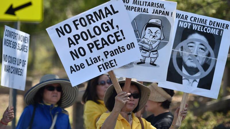 Protesters hold signs before the arrival of Japan’s prime minister Shinzo Abe at Tesla headquarters in Palo Alto, California, on Thursday.  Photograph: Josh Edelson/AFP/Getty Images