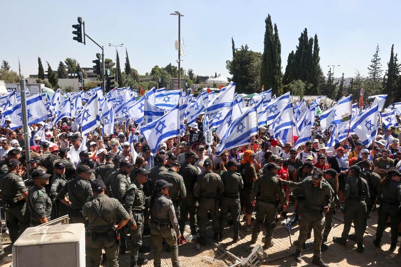 Israeli security forces stand guard as protesters wave the national flag at the entrance of the Knesset on Monday. Photograph: Menahem Kahana/AFP via Getty