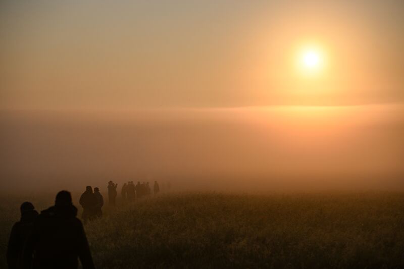 People walk through the mist as the sun rises at Stonehenge. Photograph: Finnbarr Webster/Getty