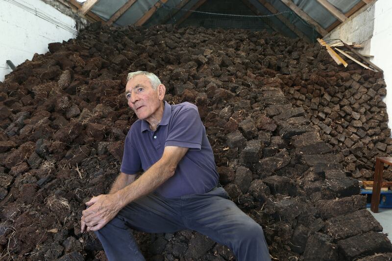 Matt Corbett sits on a pile of turf for the coming winter in a shed at his home in Ard West, Carna. Photograph: Joe O'Shaughnessy