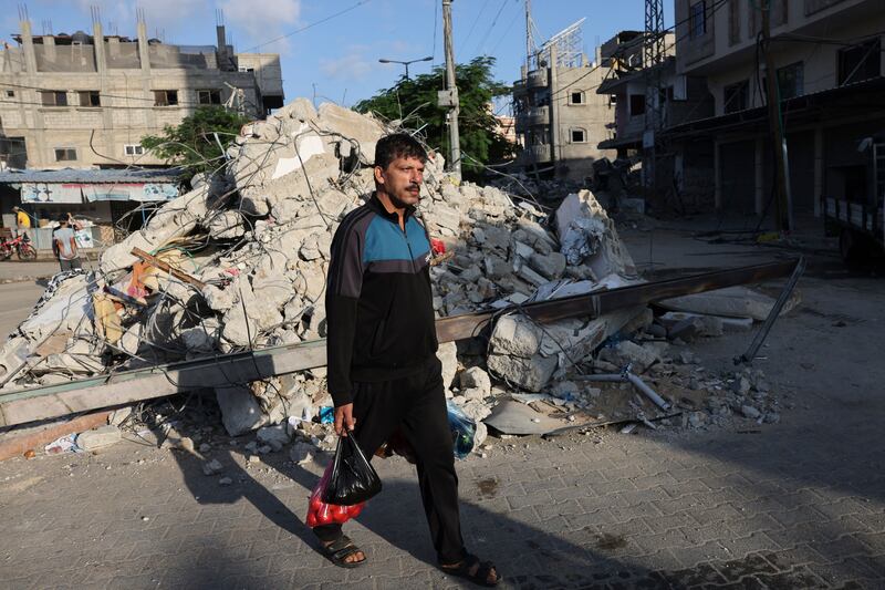 A man carrying bags of food walks in front of the rubble of a destroyed building at a market in Rafah in the southern Gaza Strip. Photograph: Mohammed Abed/AFP via Getty