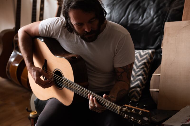 Darragh Lynch sitting oown, playing a guitar