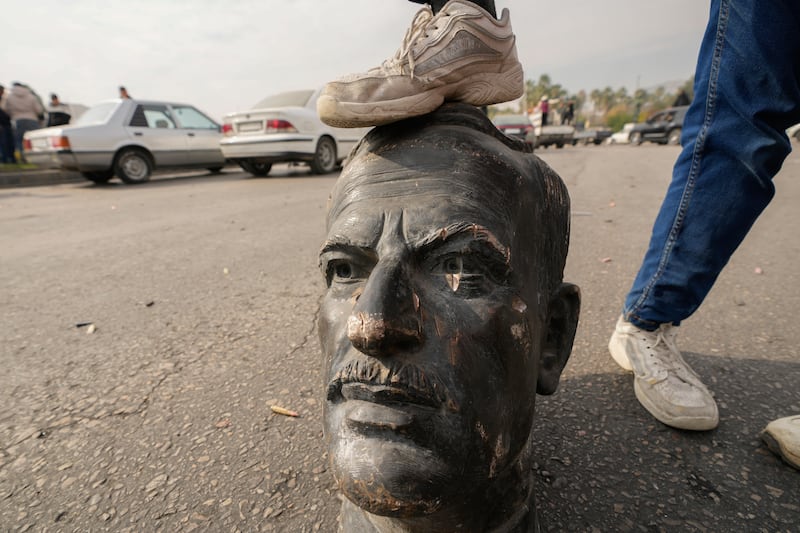 An opposition fighter steps on a broken bust of the late Syrian president Hafez Assad in Damascus following the downfall of the government of his son Bashar. Photograph: Hussein Malla/AP