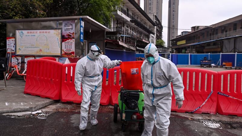 Workers in protective suits walk next to Huanan seafood market in Wuhan in 2021. Photograph:  Hector Retamal/AFP via Getty Images