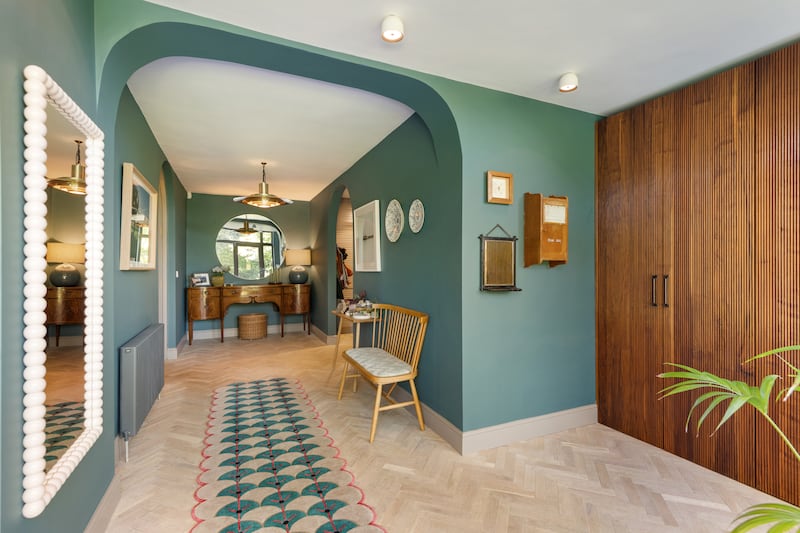 Double glass-panelled front doors open into the wide hallway, which has a series of arches and curved architraves