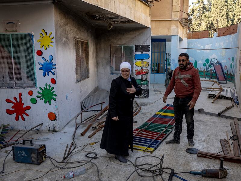 Muna Armanazi,  principal of a private school in Idlib City, works with a man to repair damage at the school following a recent airstrike. Photograph: Ivor Prickett/New York Times
                      