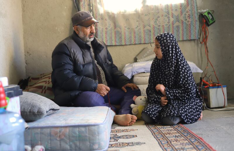 Rafiq and his daughter, Leila, collecting household items from their damaged apartment.