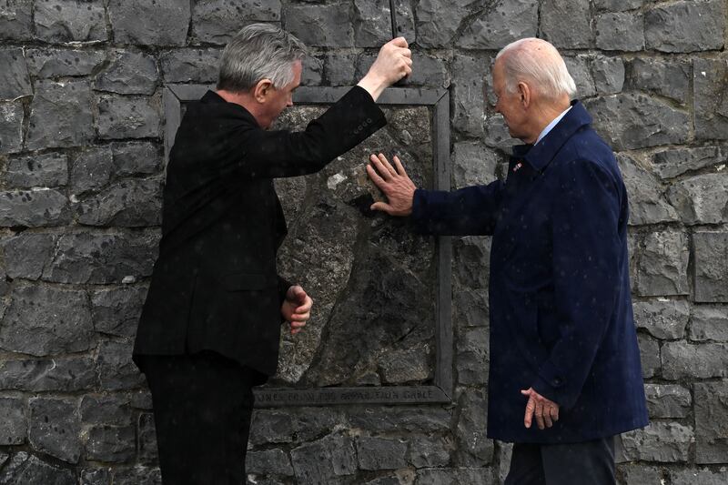 Father Richard Gibbons, parish priest at Knock, and US President Joe Biden share an umbrella as Mr Biden touches the original stone from the apparition gable in the rain during a visit to Knock Shrine on the last day of a four-day trip to Northern Ireland and the Republic. (Photo by Jim WATSON / AFP)