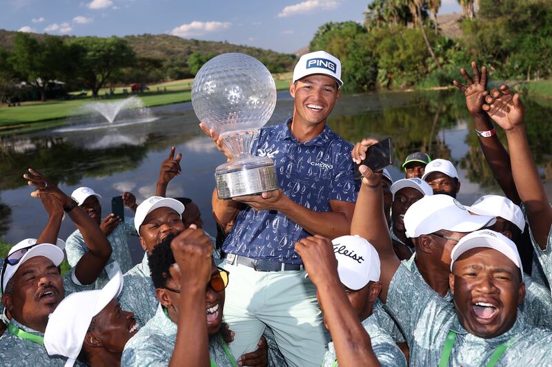 Johannes Veerman of the United States holds the trophy as he celebrates victory with ground staff on the 18th green on day four of the Nedbank Golf Challenge. Photograph: Warren Little/Getty