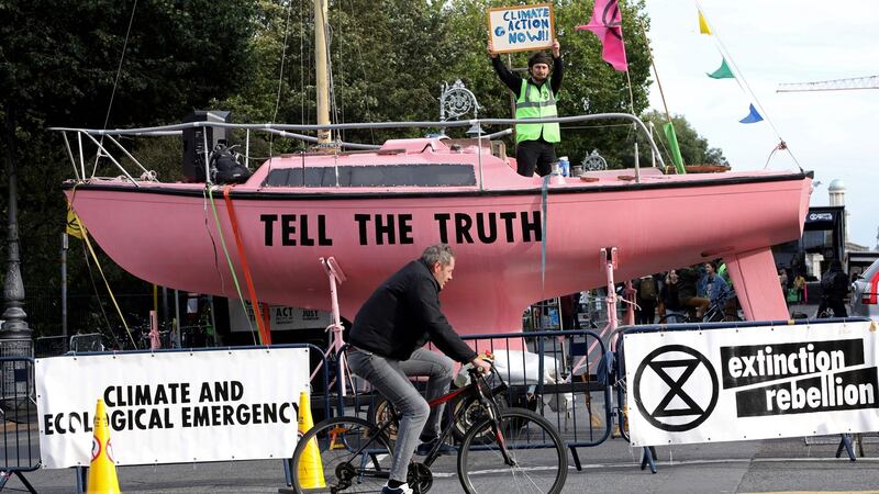 An activist stands aboard a pink boat blockading a road near Government Buildings during  Extinction Rebellion protests in Dublin. There is now unprecedented public engagement and willingness to take action on carbon emissions. Photograph: Paul Faith/AFP via Getty