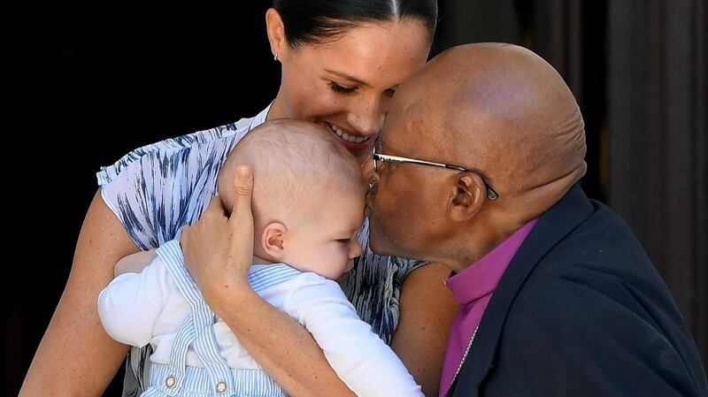 Archbishop Desmond Tutu kisses Archie Mountbatten-Windsor on the head as he is held by his mother Meghan Markle. Photograph:  Toby Melville/Getty Images