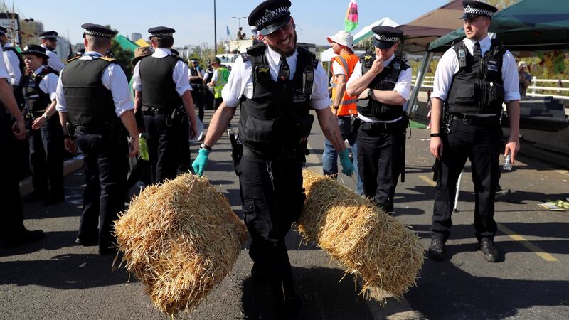 A police officer removes haystacks during the Extinction Rebellion protest on Waterloo Bridge in London. Photograph: Simon Dawson/Reuters