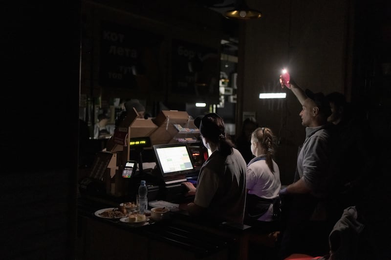 A cashier uses his phone torch to serve customers in a restaurant with no electricity during a blackout in Kyiv on Thursday. Photograph: Roman Pilipey/AFP via Getty Images