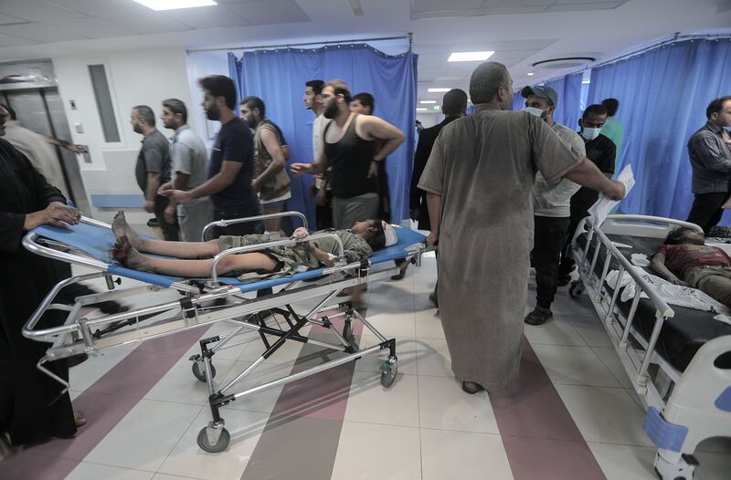 Wounded Palestinians lie on stretchers at Al-Shefa hospital in Gaza City: The UN estimates nearly 300,000 Palestinians have been displaced with many rushing to UN-run schools and refugee camps to seek shelter from the Israeli bombardment.