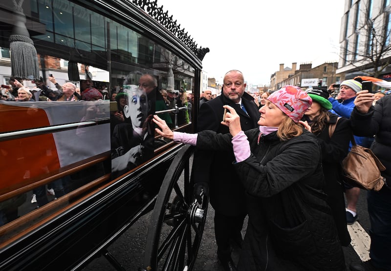 Members of the public touch the glass window of the carriage as the funeral procession of the late singer Shane MacGowan takes place in Dublin. Photograph: Charles McQuillan/Getty