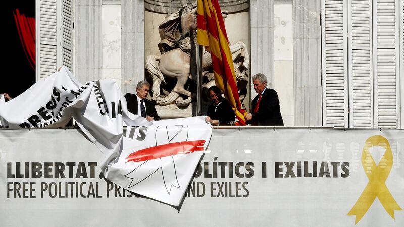 Staff replace a banner with another one with the same message but depicting a white ribbon  instead of the previous yellow one, at the Catalan regional government headquarters, in Barcelona. Photogrpah: EPA/Toni Albir