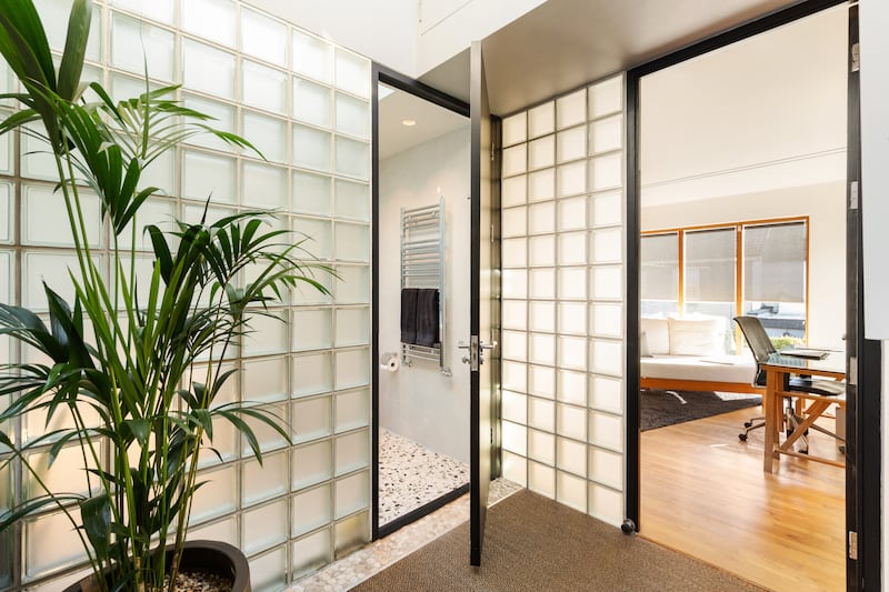 Hallway featuring glazed block wall of shower room and door to fourth bedroom