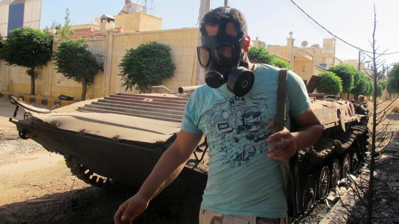 A Free Syrian Army fighter wearing a gas mask, carries his weapons as he walks past a damaged tank, after seizing a government military camp used by forces loyal to Syria’s President Bashar al-Assad, near Idlib, yesterday. Photograph: REUTERS/Abdalghne Karoof