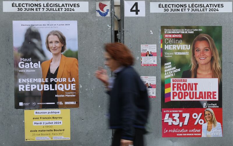 A woman walks past a poster for Nouveau Front Populaire 'The New Popular Front' candidates for the parliamentary elections in Paris. 