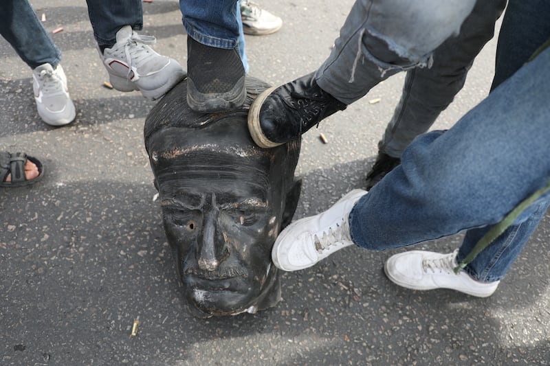 People show their contempt for a vandalised statue of Hafez al-Assad, father of Bashar al-Assad, in Umayyad Square, Damascus. Photograph: Ali Haj Suleiman/Getty